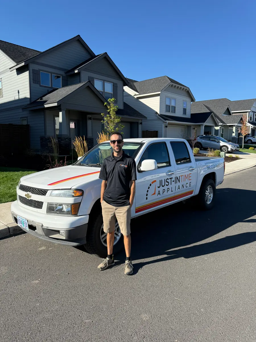 Just-in Time technician standing beside a branded service truck in a neighborhood