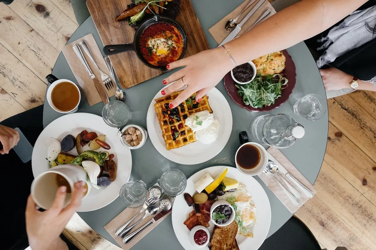 Overhead shot of breakfast spread with waffles, eggs, and coffee on a table