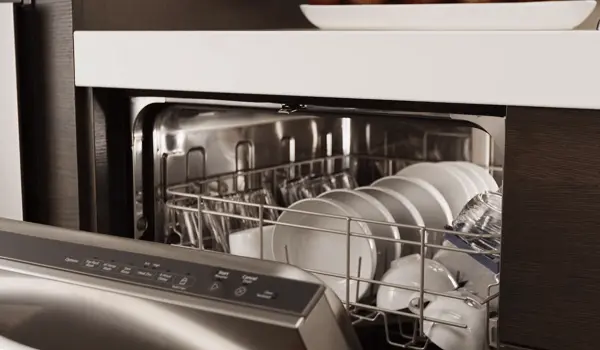 Open stainless steel dishwasher loaded with plates and glassware