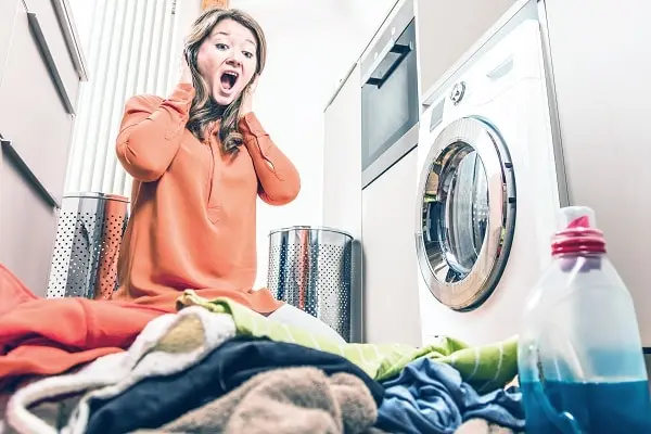 Woman surprised by a noisy washer or dryer in a laundry room