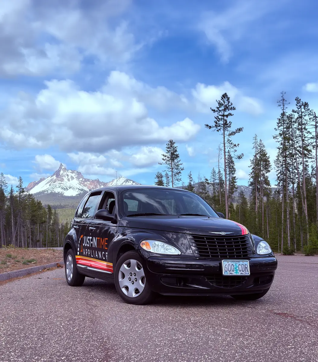 Black Just-in Time Appliance Repair branded vehicle in front of Oregon mountains